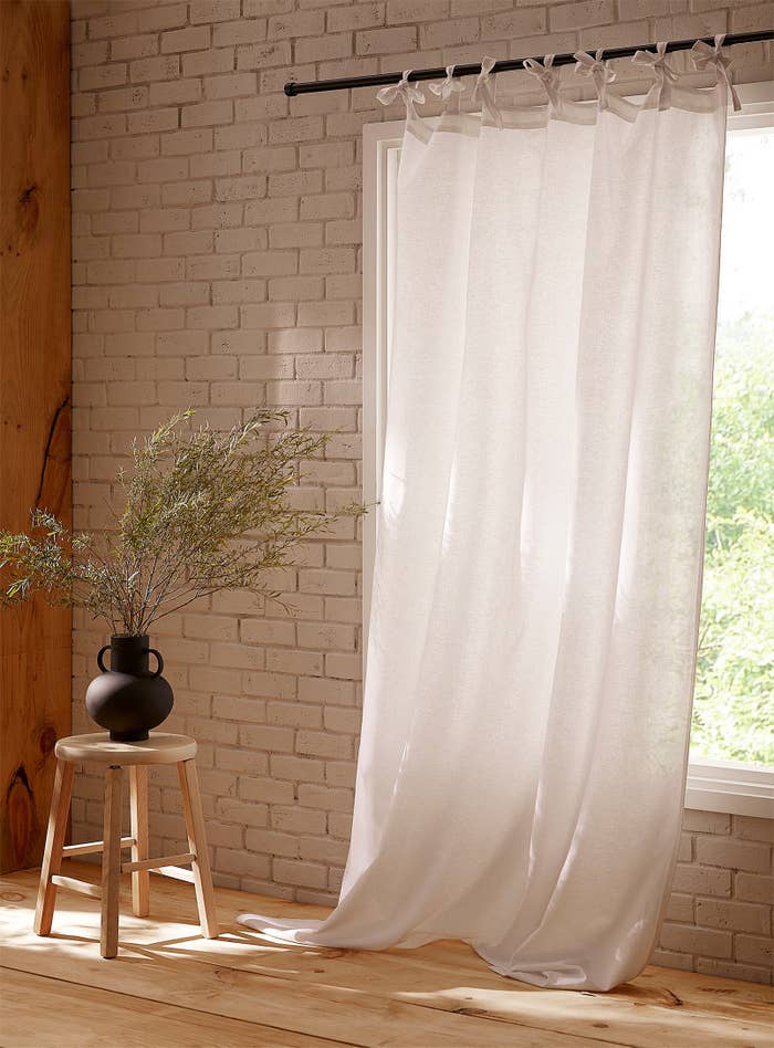 The curtain hanging up in a room in front of a window