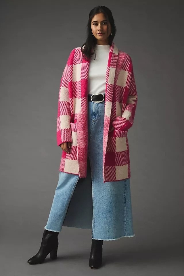 Model wearing pink and white plaid cardigan over white top and jeans