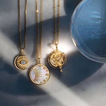 three gold charm necklaces with heavenly themes