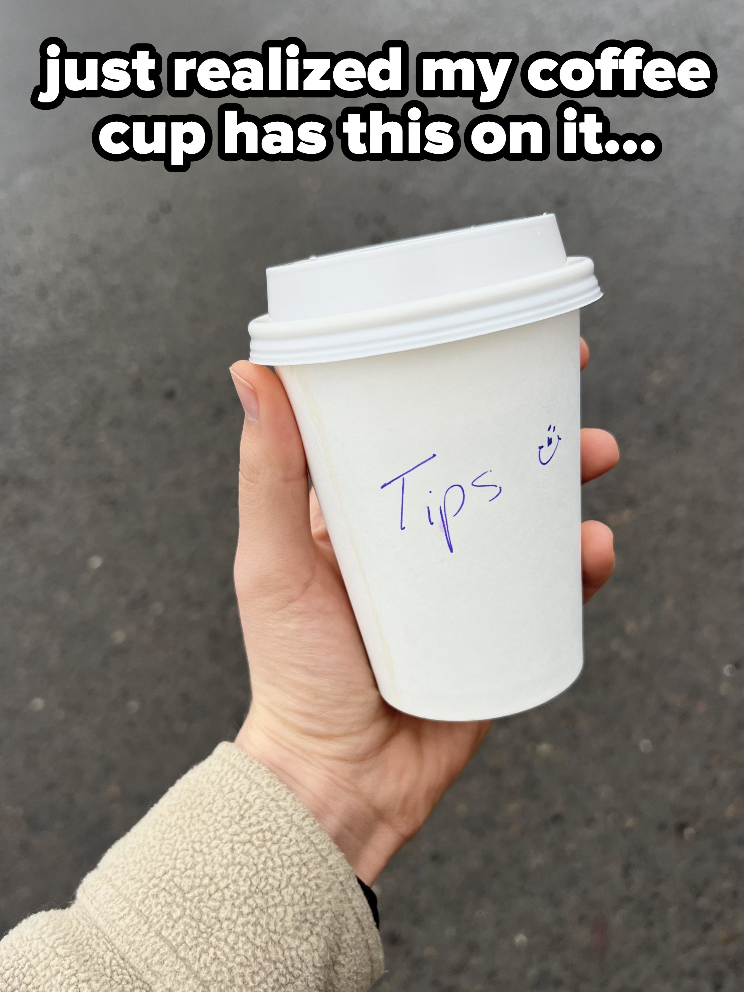 Person holding up a coffee cup with &quot;Tips&quot; written on it