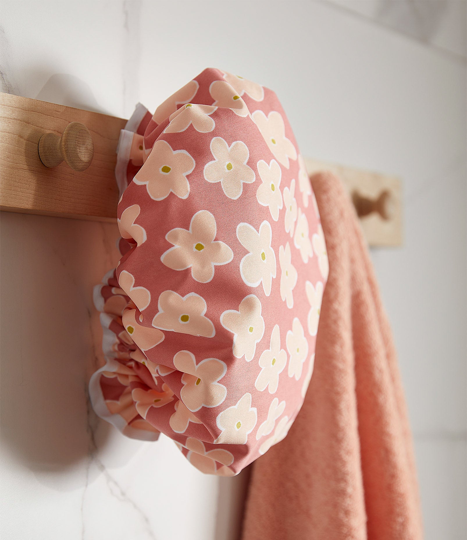 a floral shower cap hanging in a bathroom next to a towel