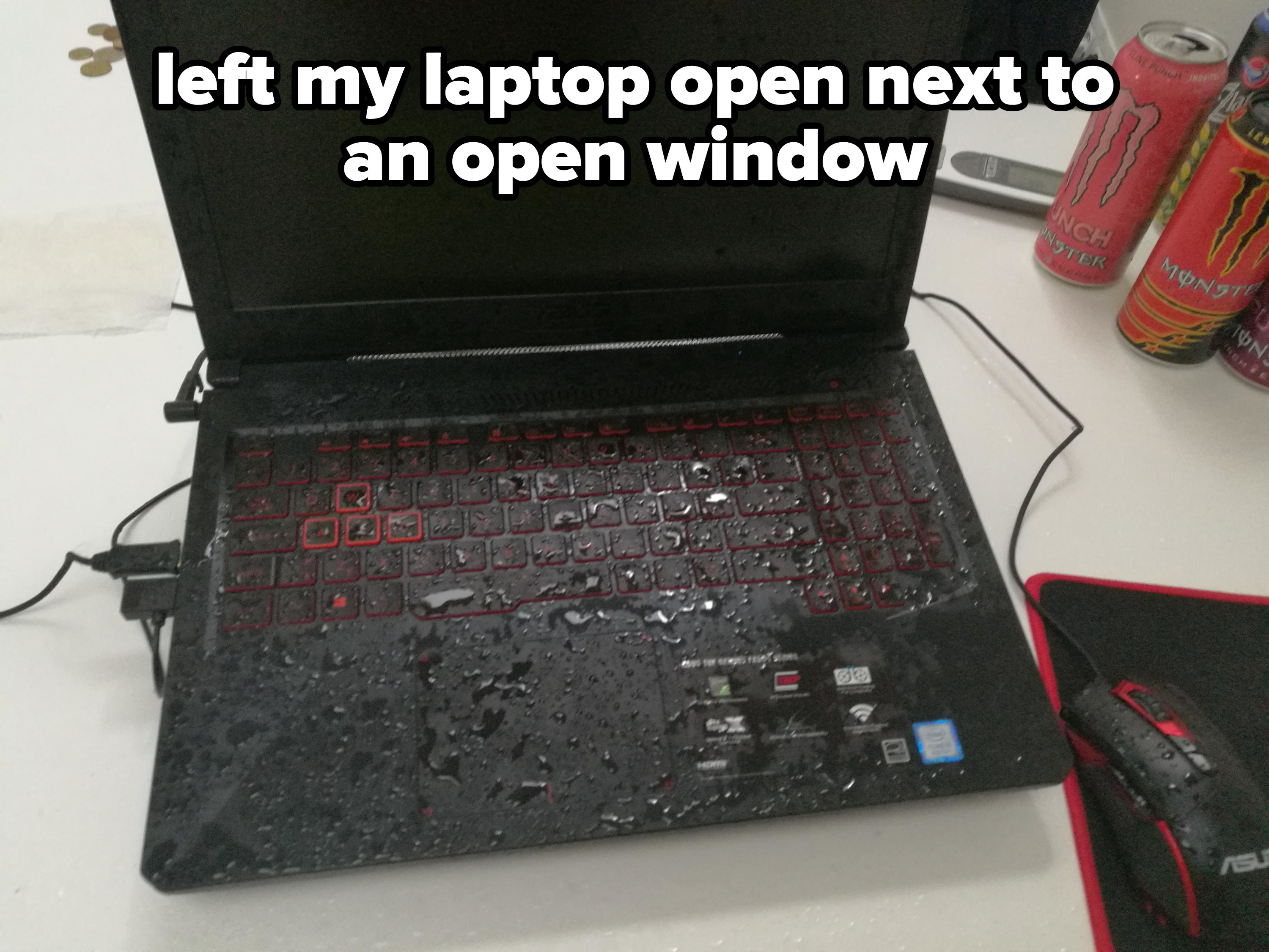 The keyboard of a laptop left next to an open window with water on it