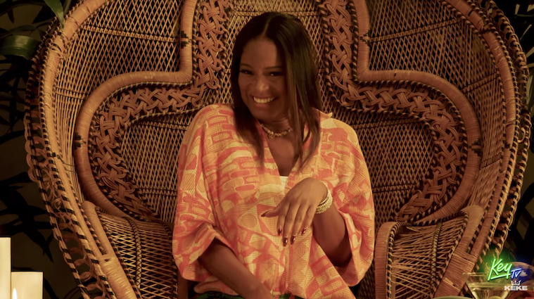 Keke sitting in a large wicker chair and smiling