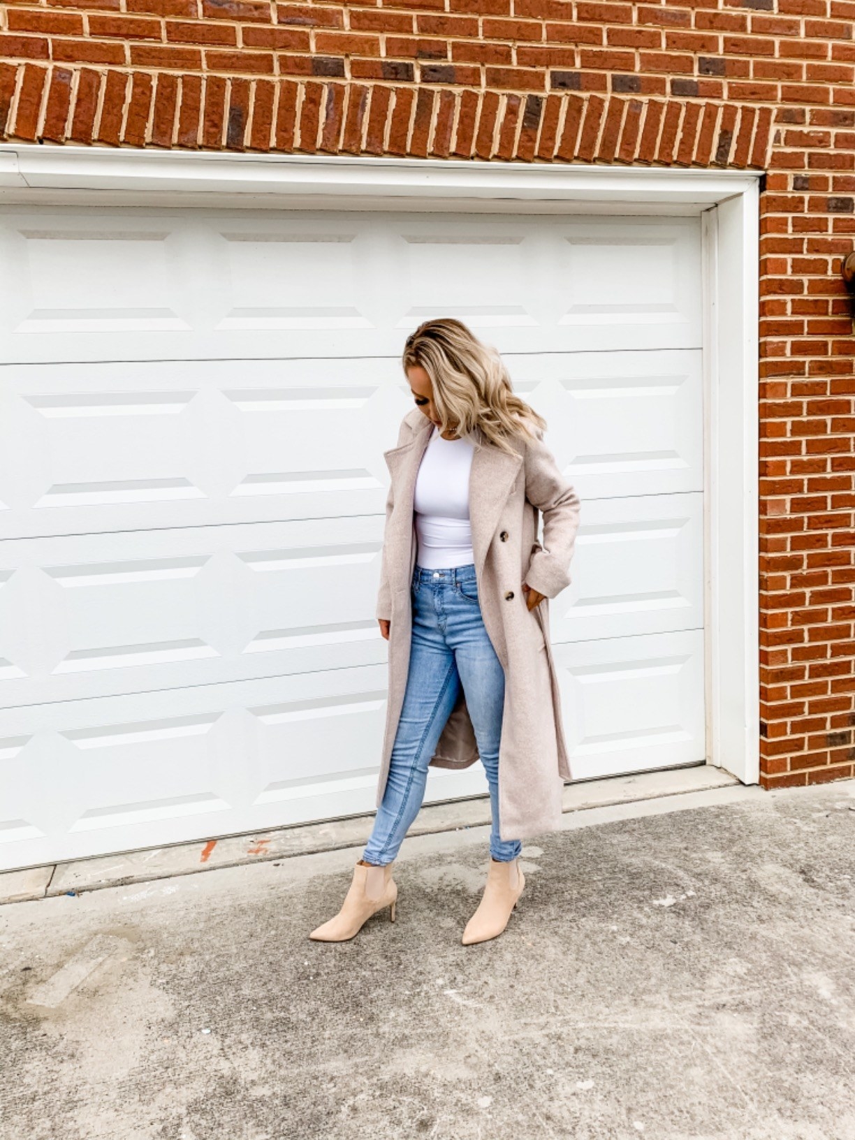 Reviewer outside in white tank bodysuit worn under long pea coat