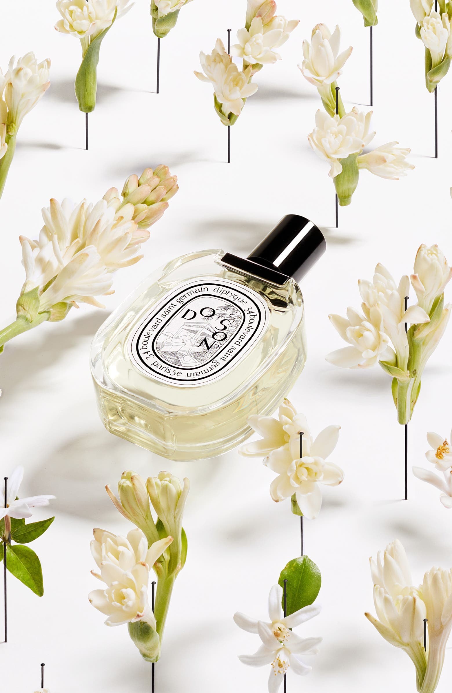 a diptyque perfume bottle lying in flowers