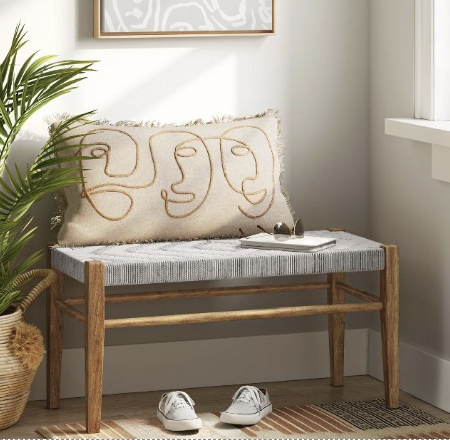 A grey colored bench by a window