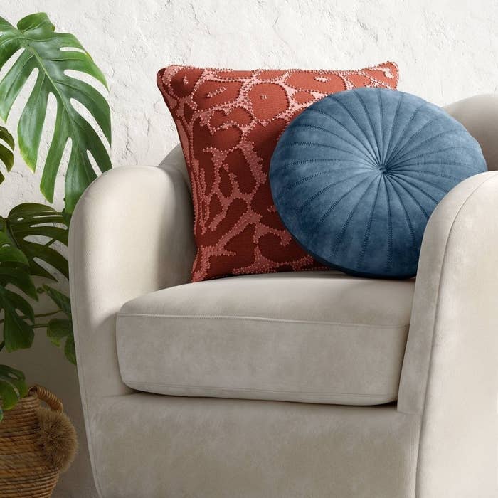 the round blue pillow on an off-white barrel chair