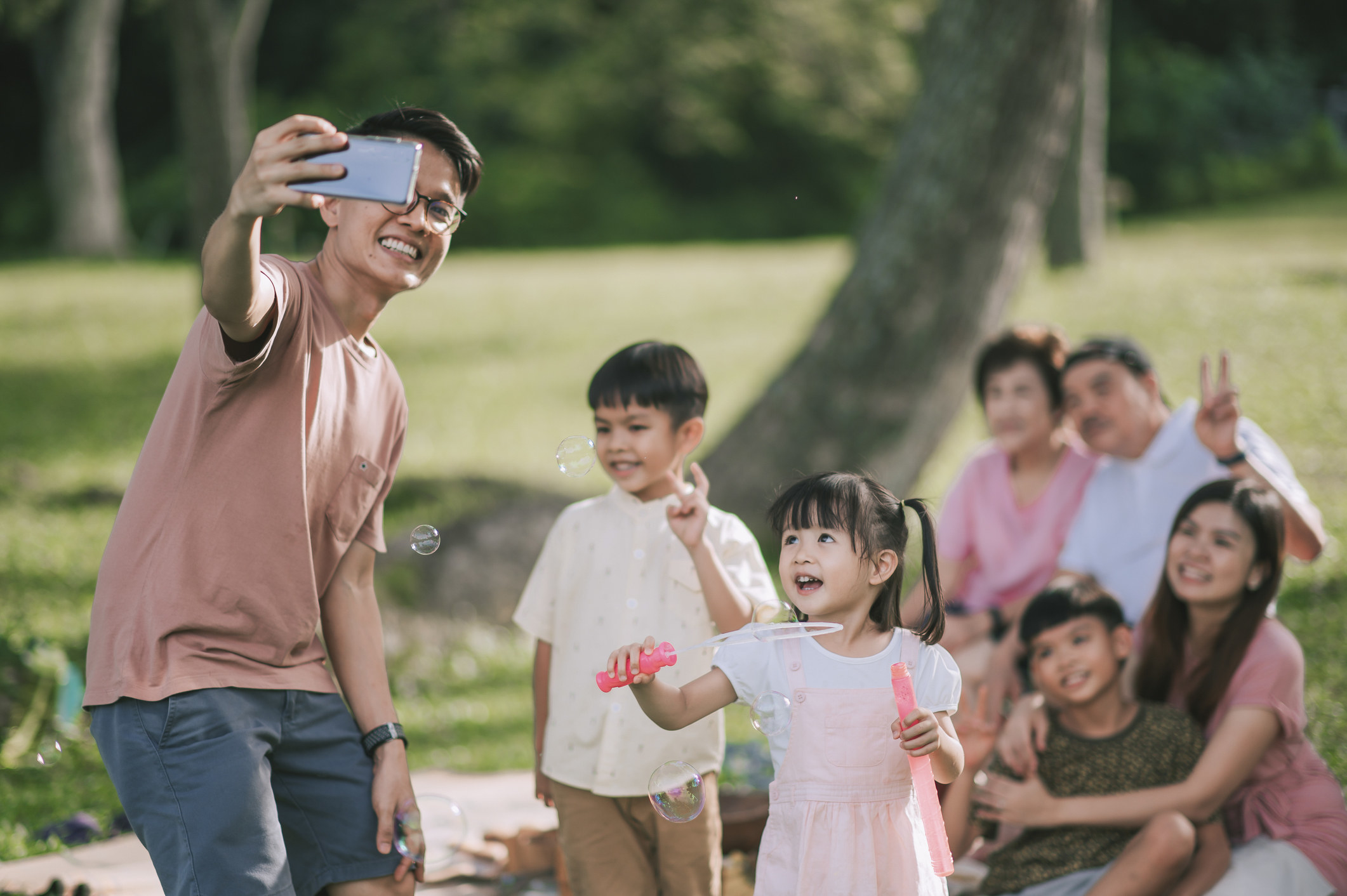 young dad taking selfie with the whole family at a park