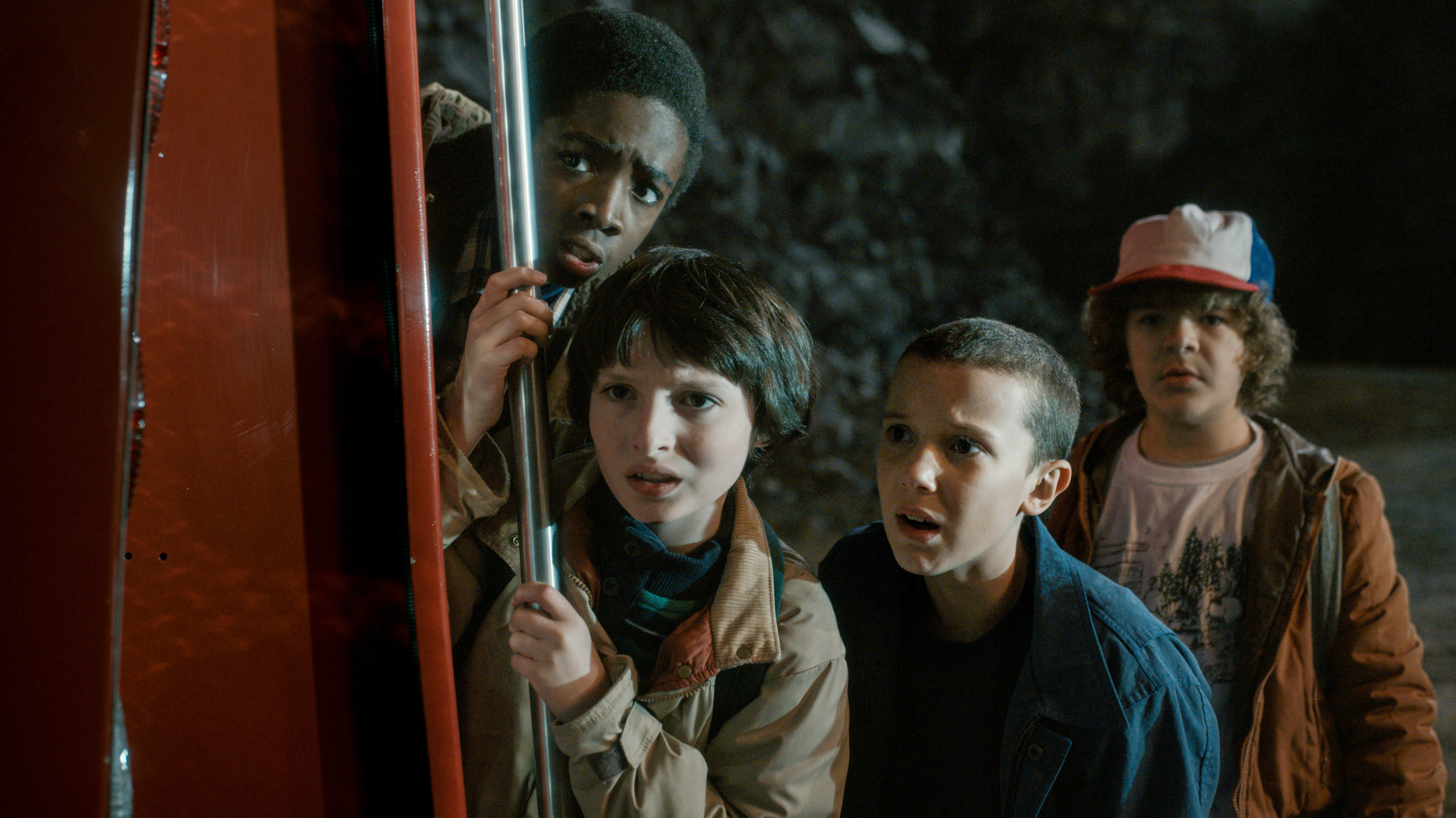 Mike, Eleven, Lucas, and Dustin carefully peeking at something