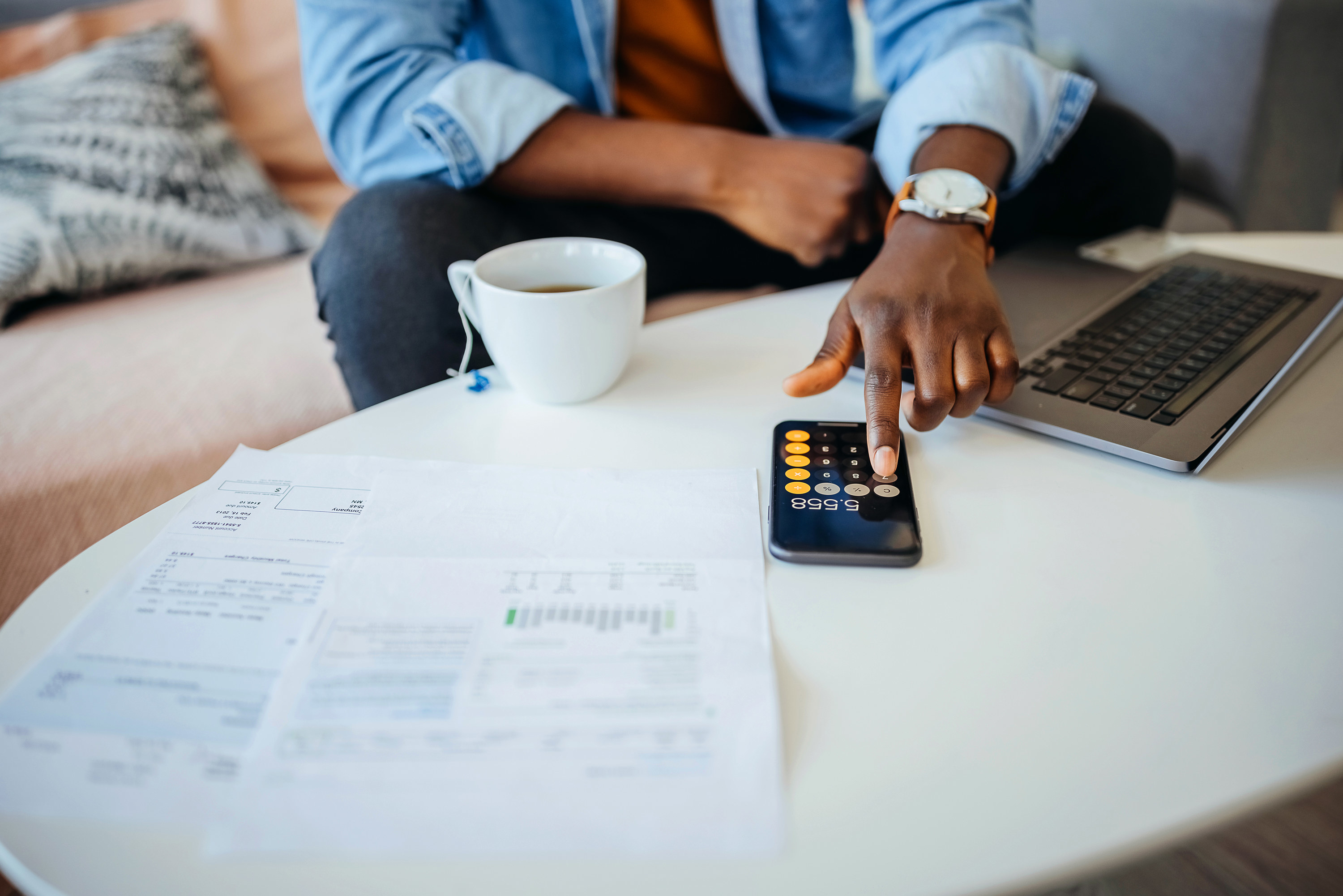 hand on a calculator with papers spread on a table