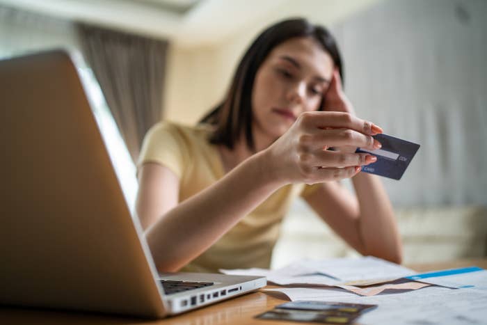 Young woman looking at her credit card with a sad expression