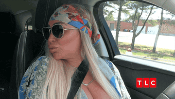 person sitting in a car with sunglasses on blowing a kiss and saying juicy