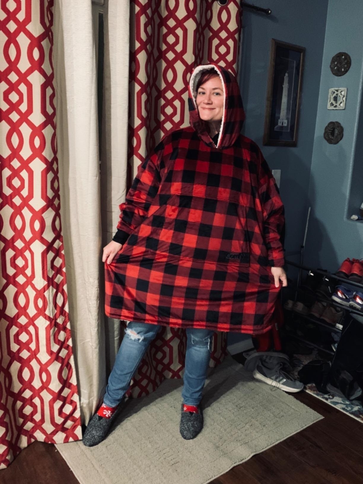 A reviewer wearing a Buffalo check Comfy demonstrating the spaciousness of the product by extending the sides