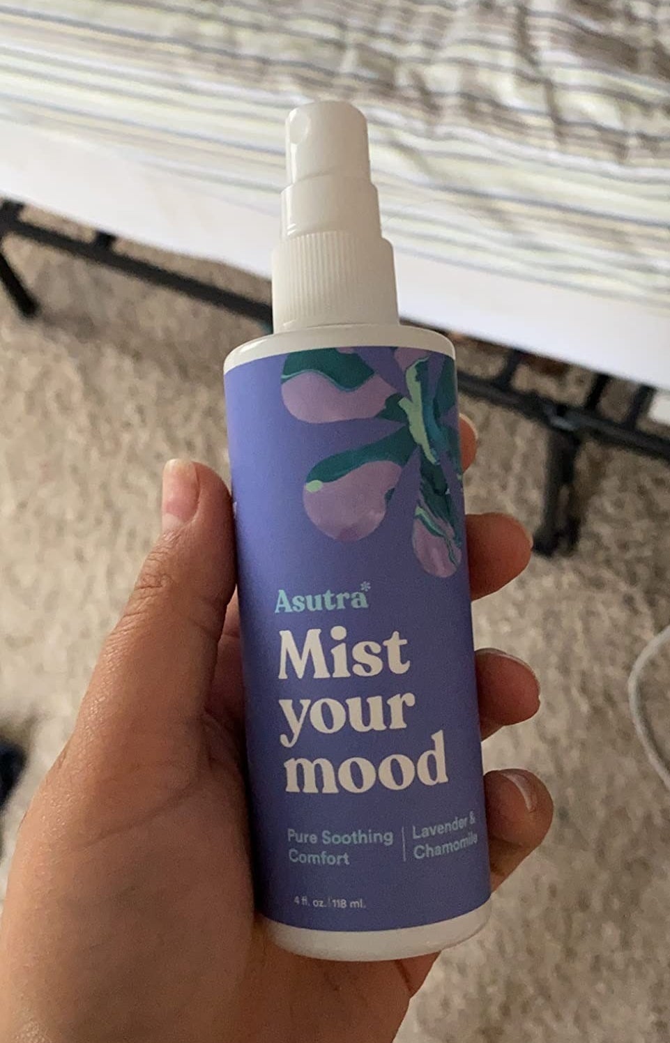 A reviewer holding the purple spray in their hand