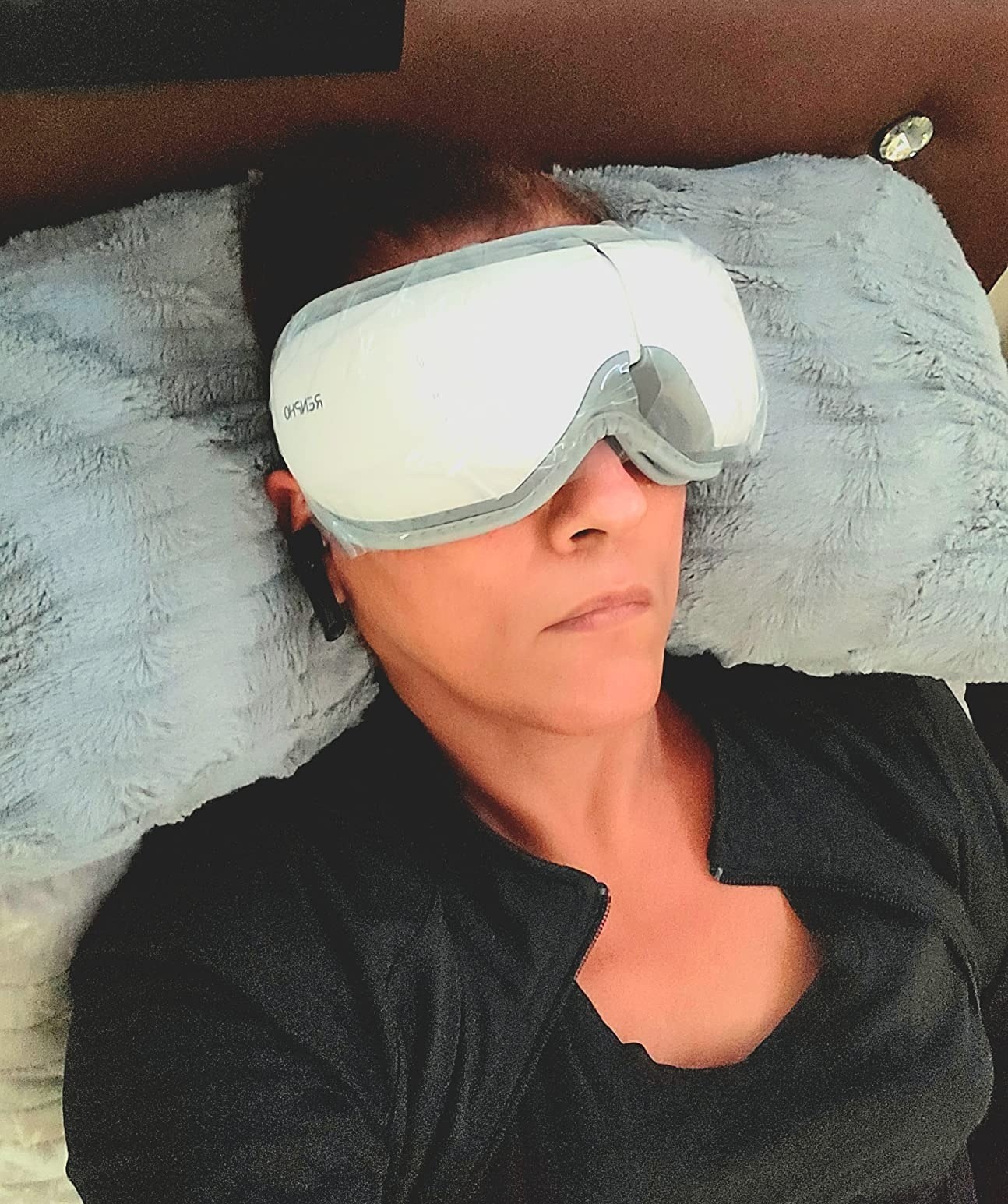 A reviewer laying down using the eye massager