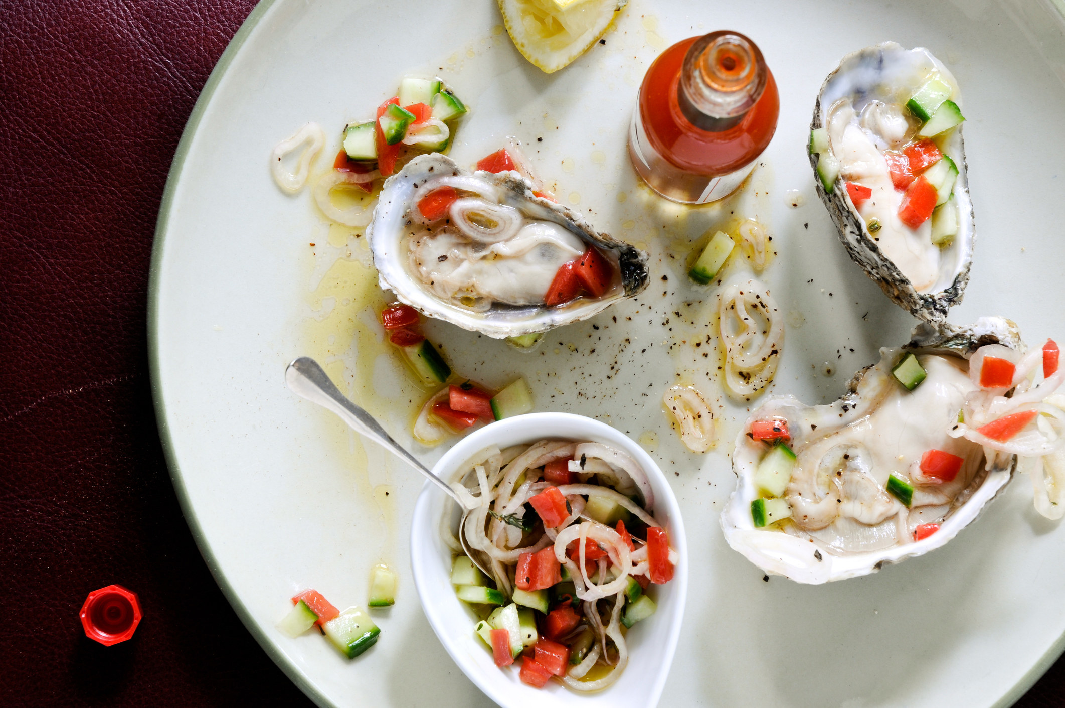 Shucked local oysters on white plate with cucumber-tomato relish and hot sauce