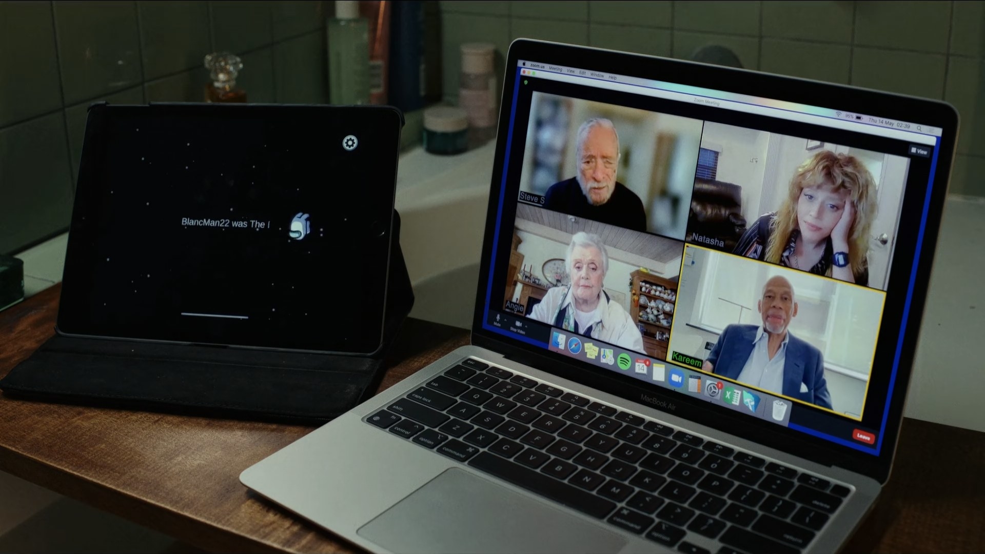 a laptop screen shows a video call in which the faces of four people appear on screen