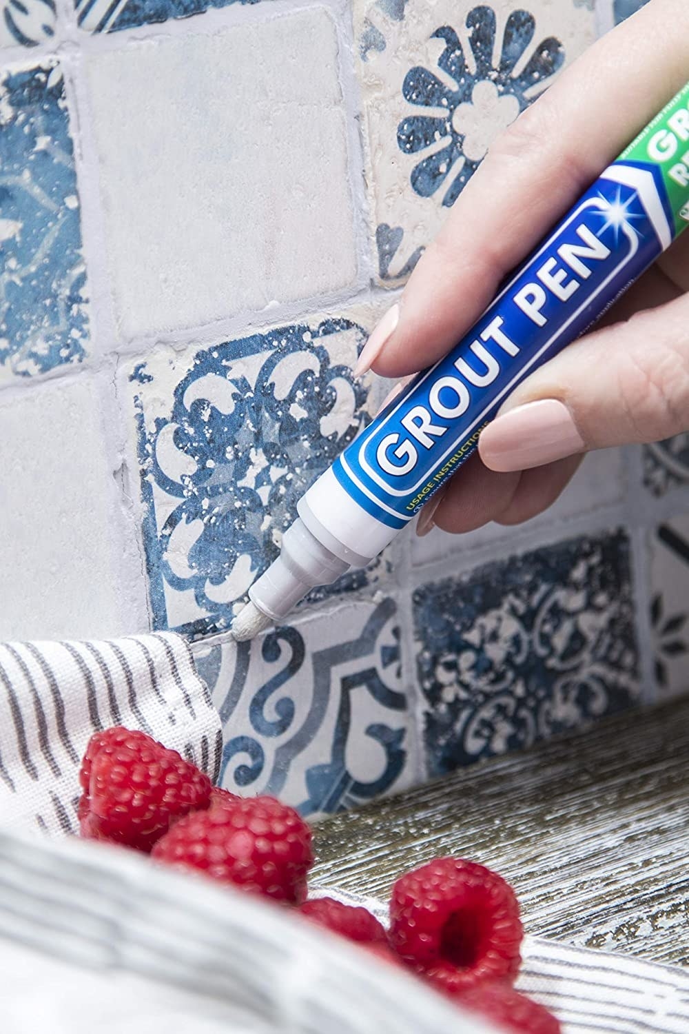 a person using the grout pen on a tile backsplash