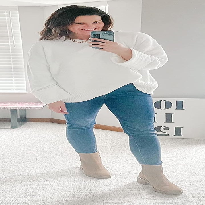 Reviewer wearing a white sweater, jeans and boots
