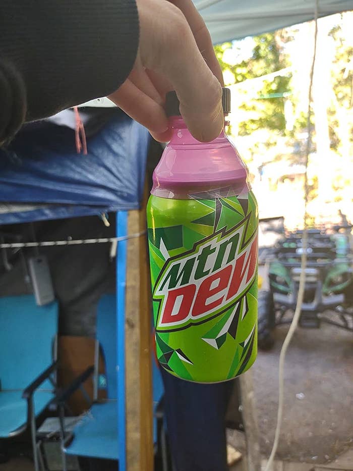 reviewer holds bottle top on can by the cap to show how secure it is