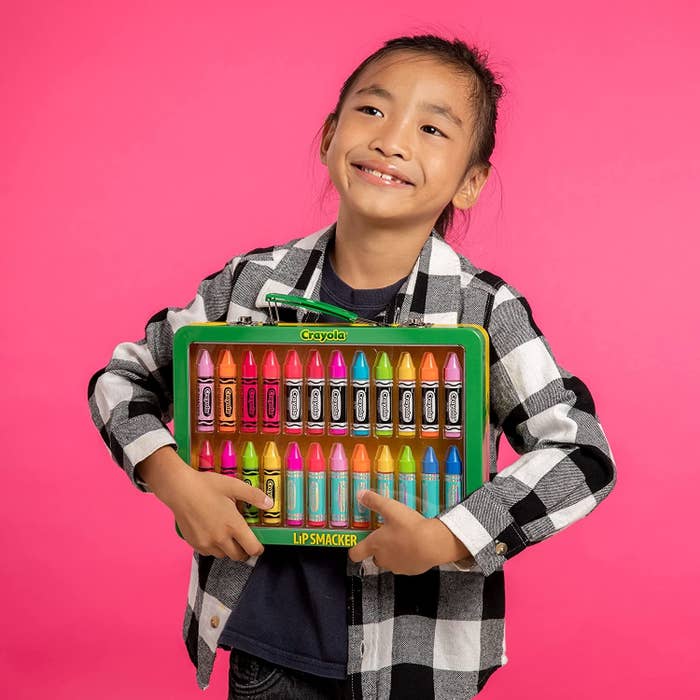 pre-teen poses with pack of crayon shaped lip balms