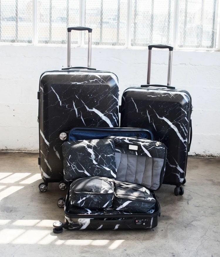 black luggage set with white marbling with three sizes of four-wheeled roller bags