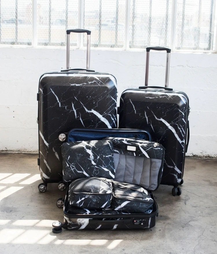black luggage set with white marbling with three sizes of four-wheeled roller bags