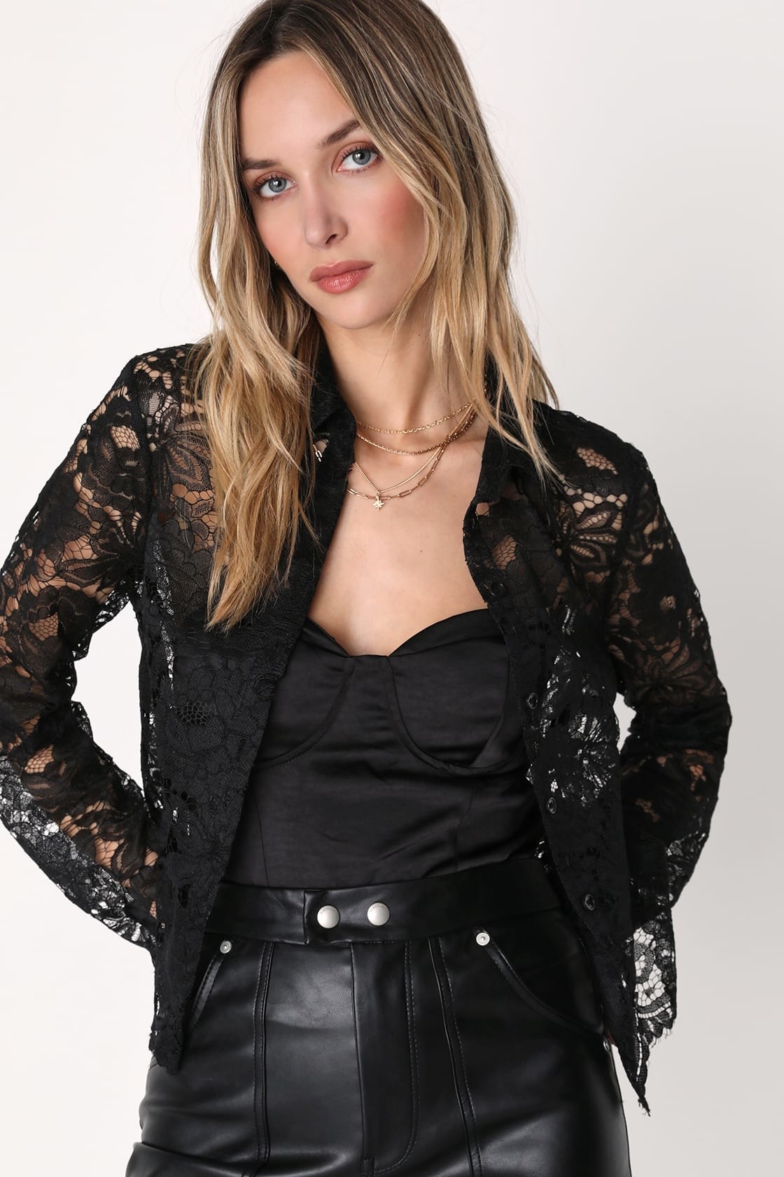 Model wearing lace top over black bustier top with black leather pants
