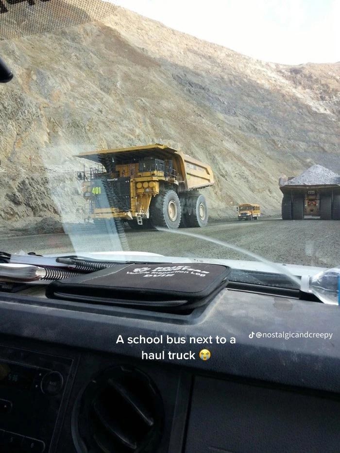 A school bus looking tiny behind a huge truck on a highway