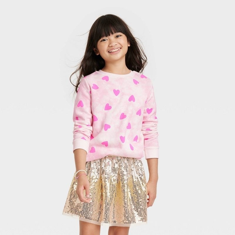 a child models the pink sweatshirt with hearts
