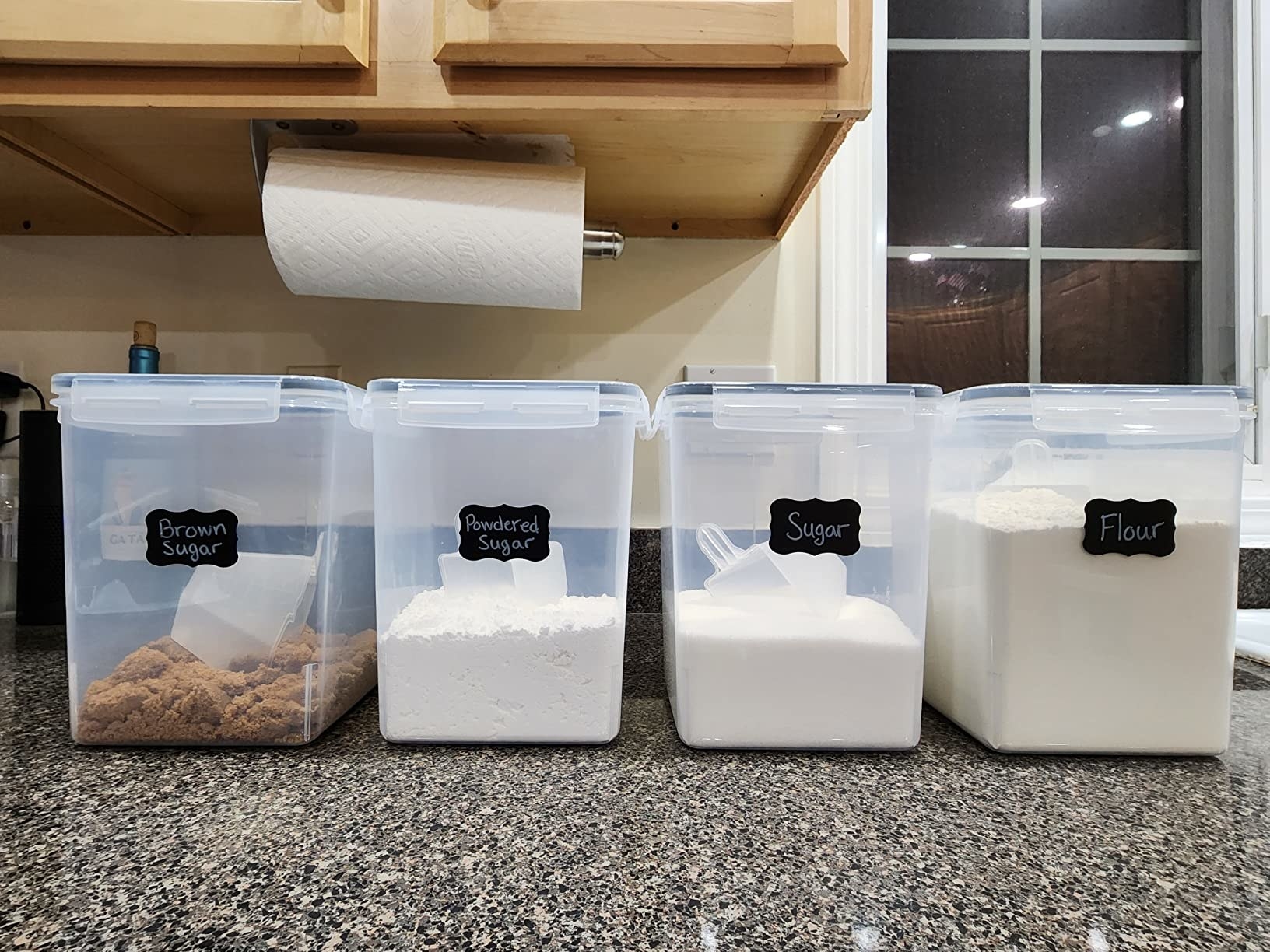 Reviewer&#x27;s photo of four containers storing brown sugar, powdered sugar, sugar, and flour lined up on counter