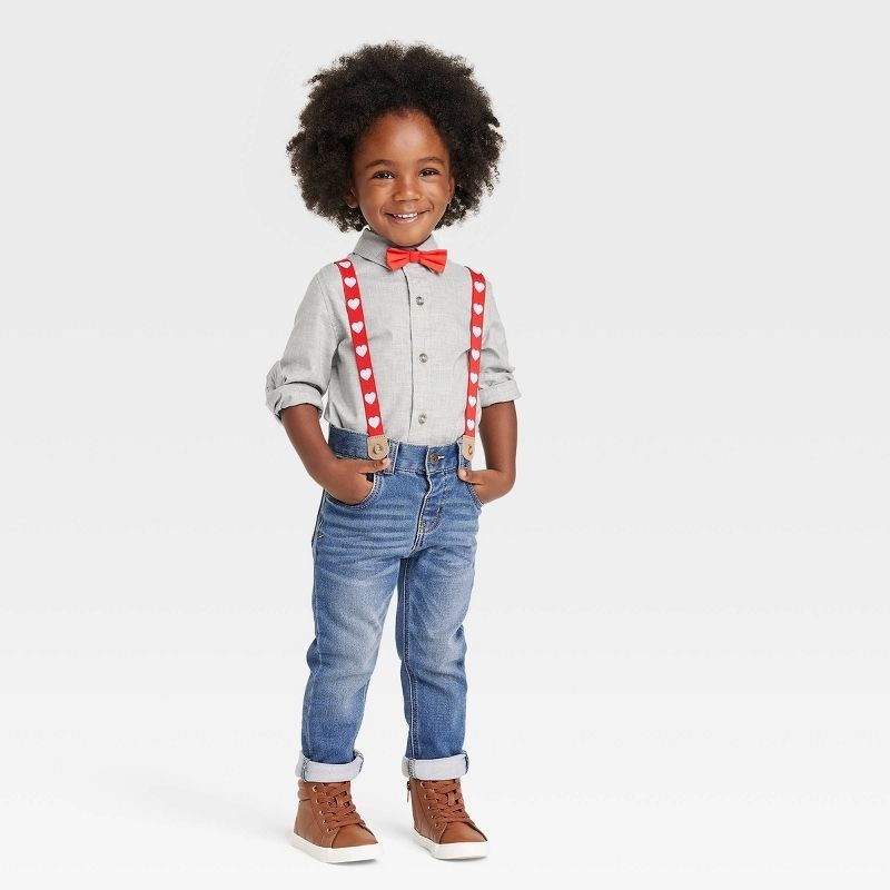 a child models the set with red heart suspenders