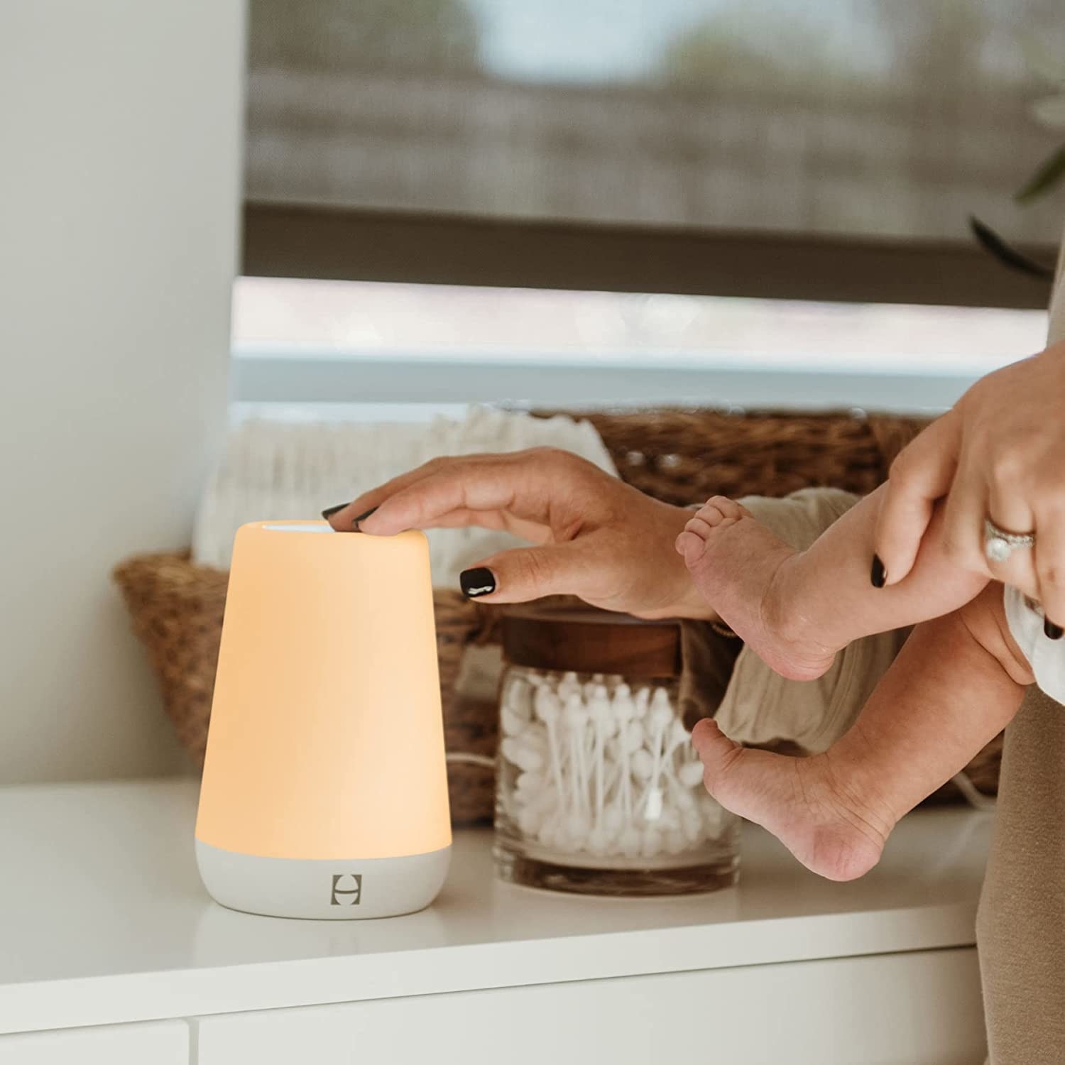 a person tapping the nightlight while holding a baby