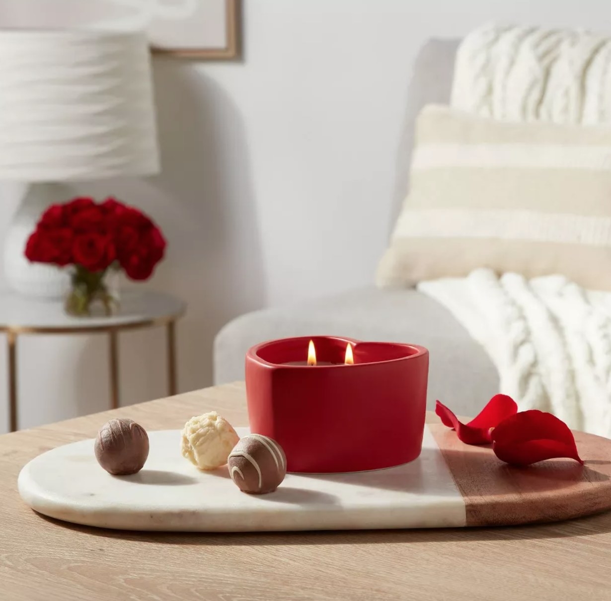 the heart shaped red ceramic candle lit on a table next to chocolate