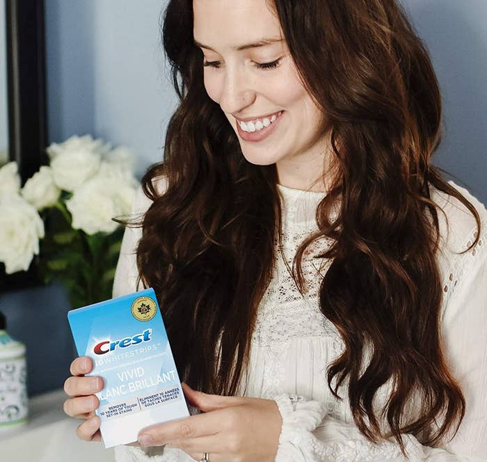 a person holding a box of crest white strips