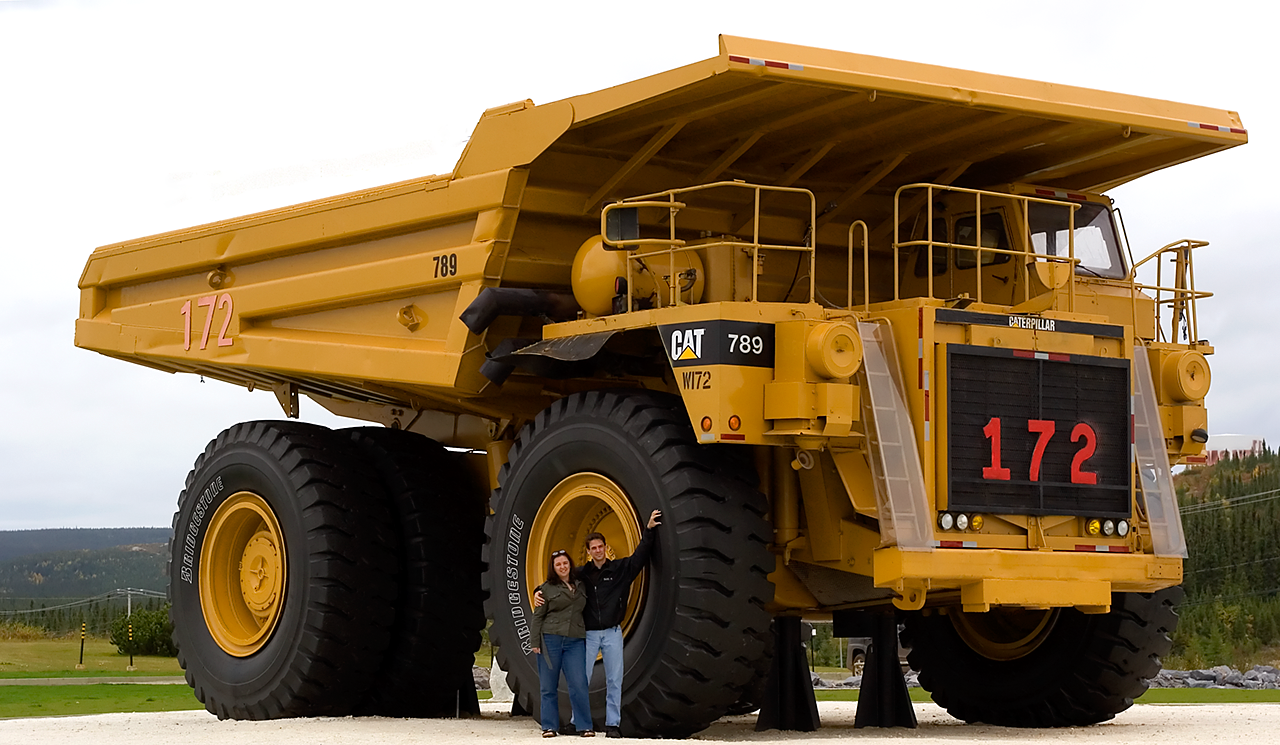 Two people standing next to a haul truck and they&#x27;re not even half as tall as a tire