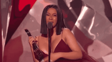 cardi holding an award on stage