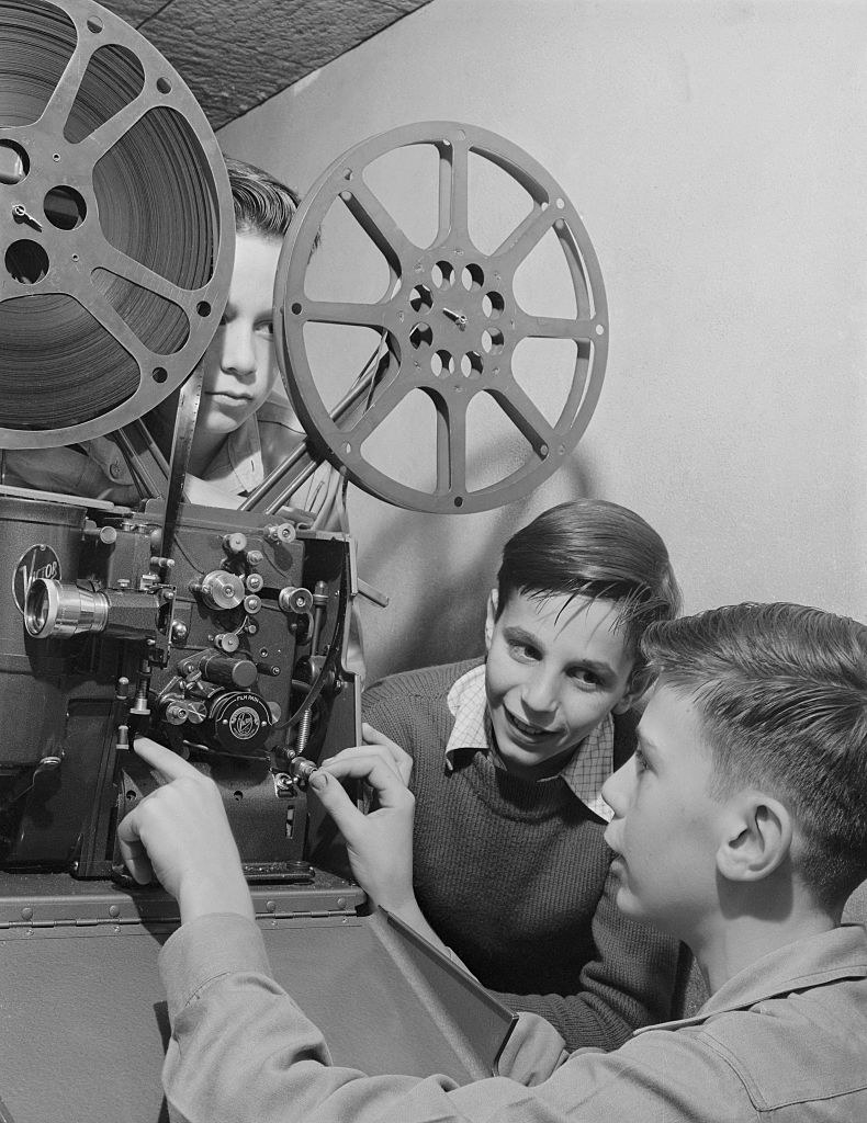 Two young men using a film projector