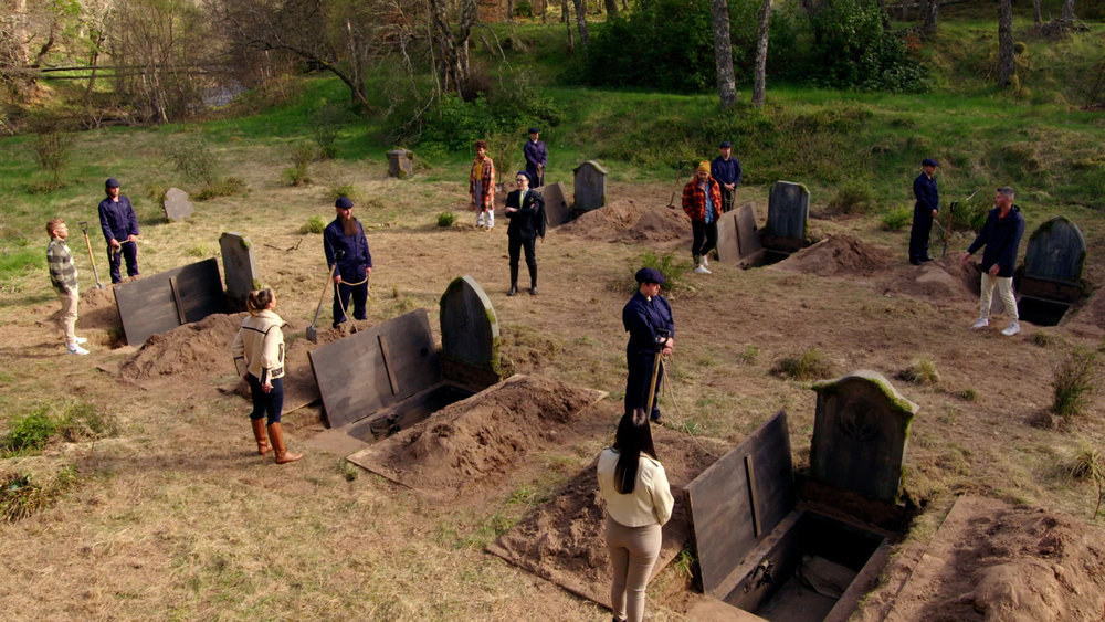Contestants stand outside graves