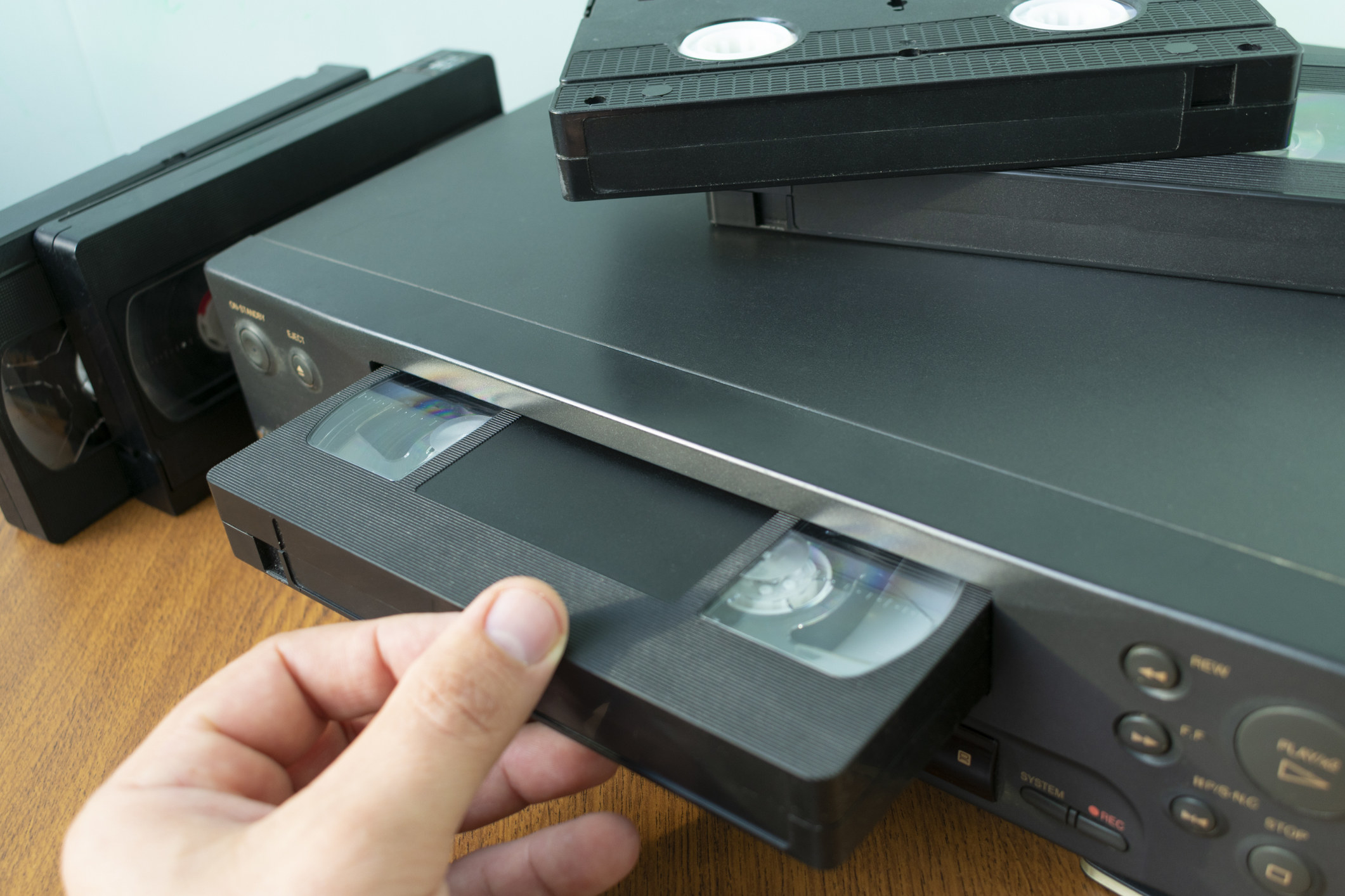 Someone putting a VHS cassette into a VCR