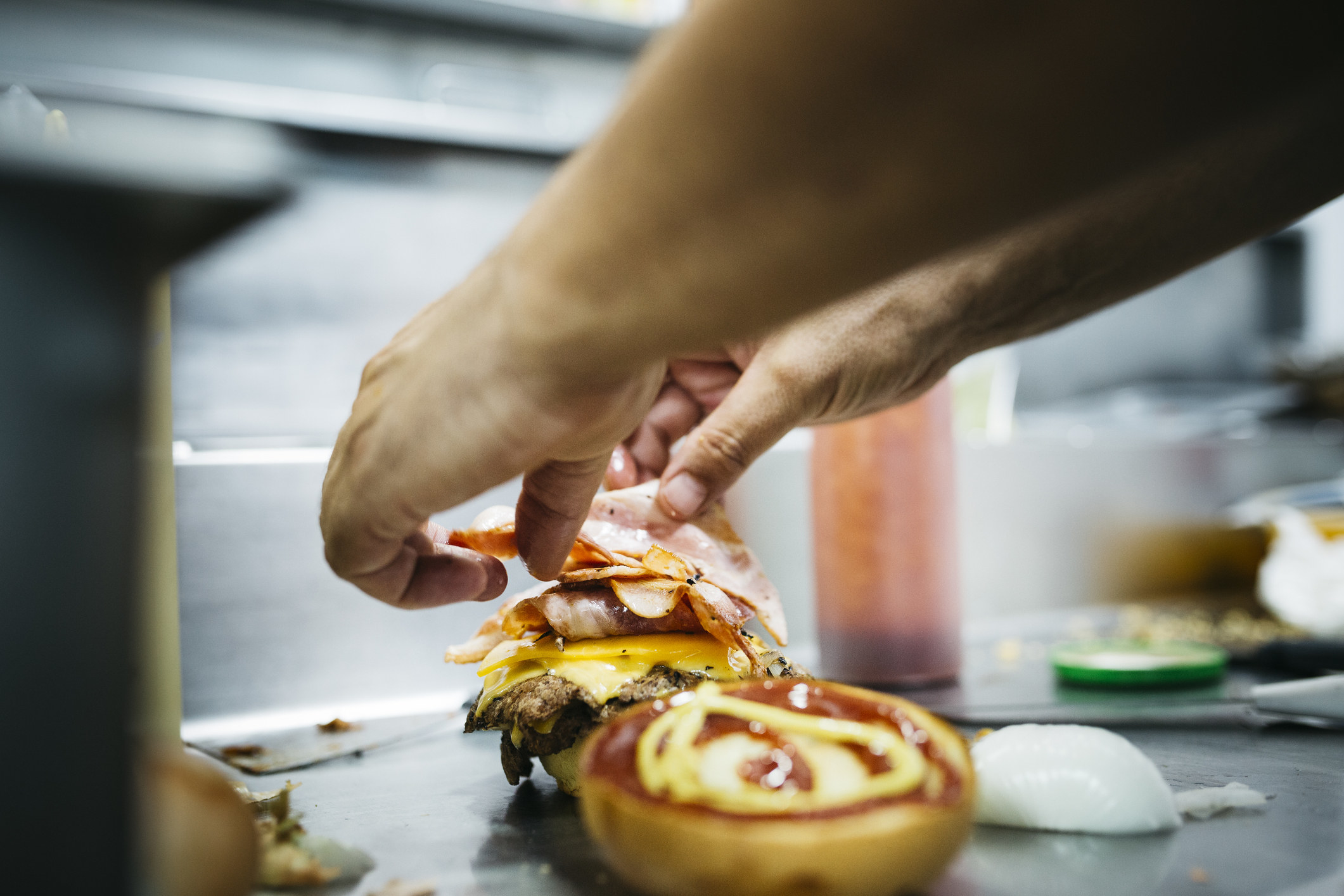 Chef preparing a cheeseburger with his hands.