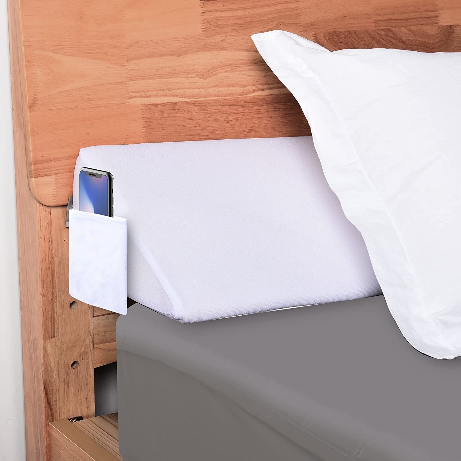 the wedge pillow under a pillow on a mattress against the headboard
