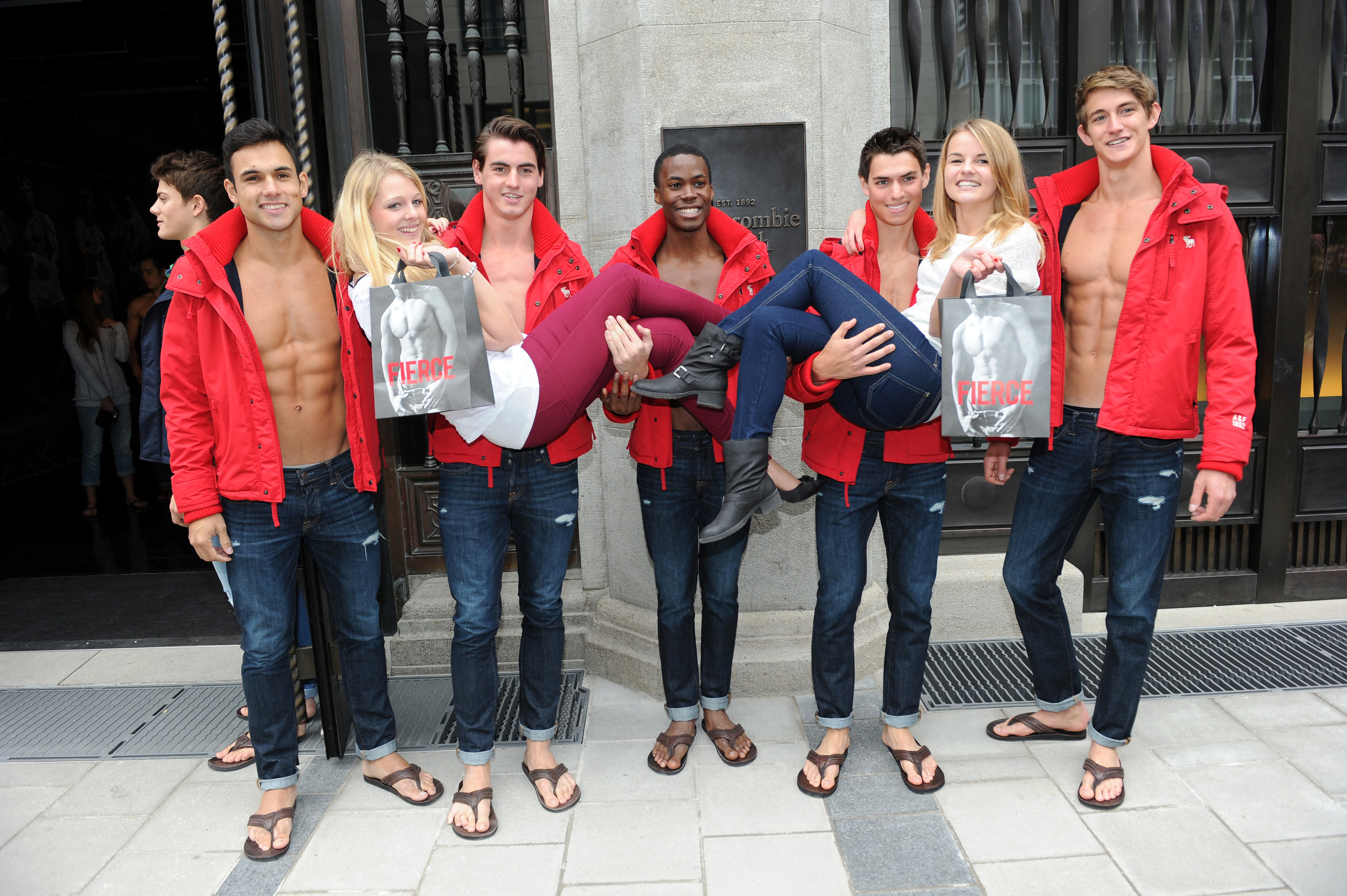 Five Abercrombie and Fitch Models hold up two women outside an Abercrombie and Fitch store