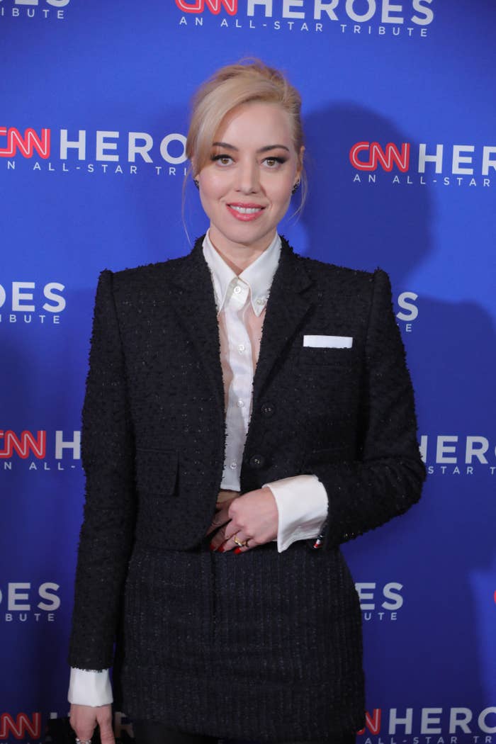 Aubrey smiles for photographers at an event while wearing a pantsuit