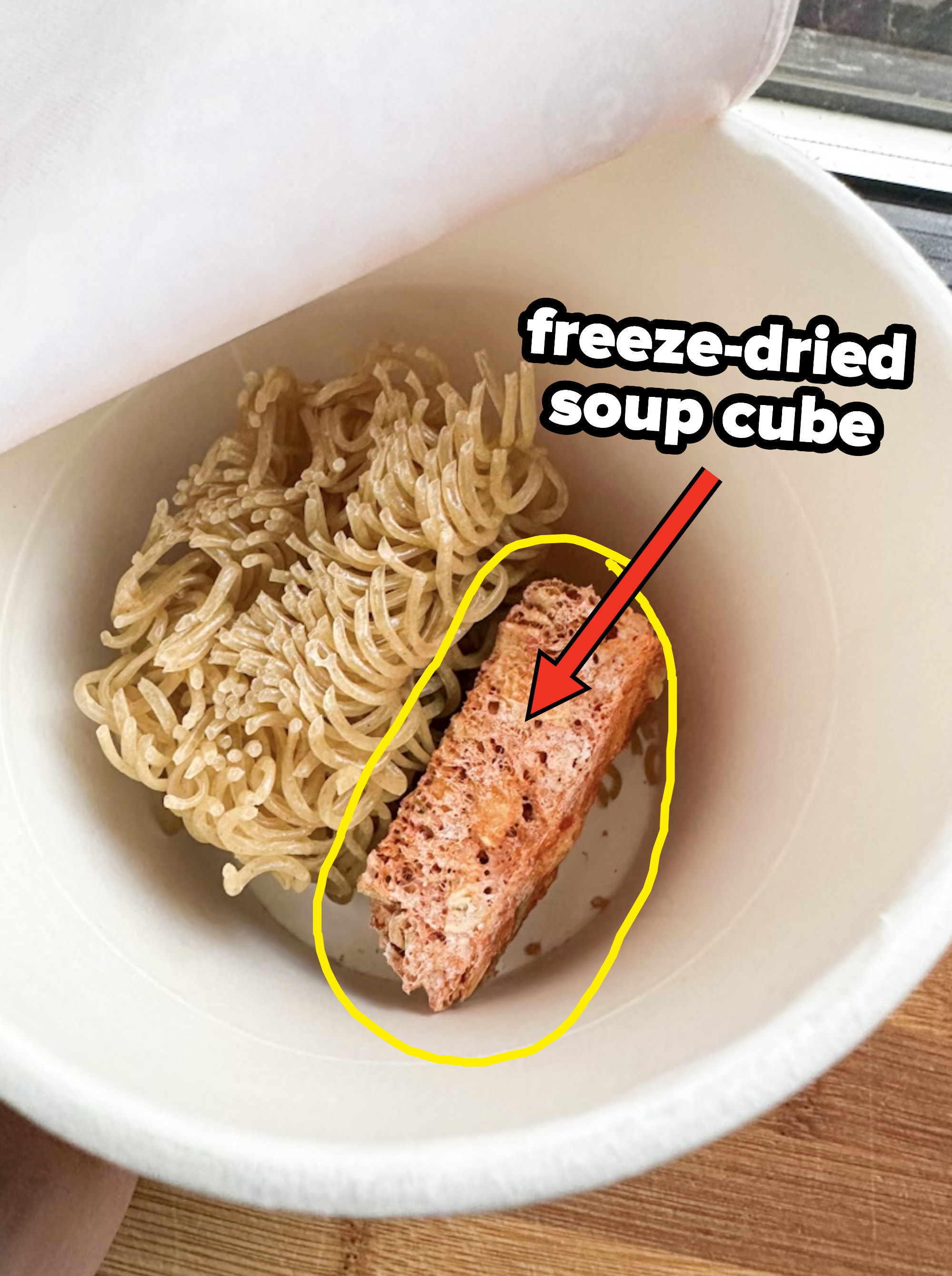 arrow pointing to freeze dried soup cube in the cardboard cup