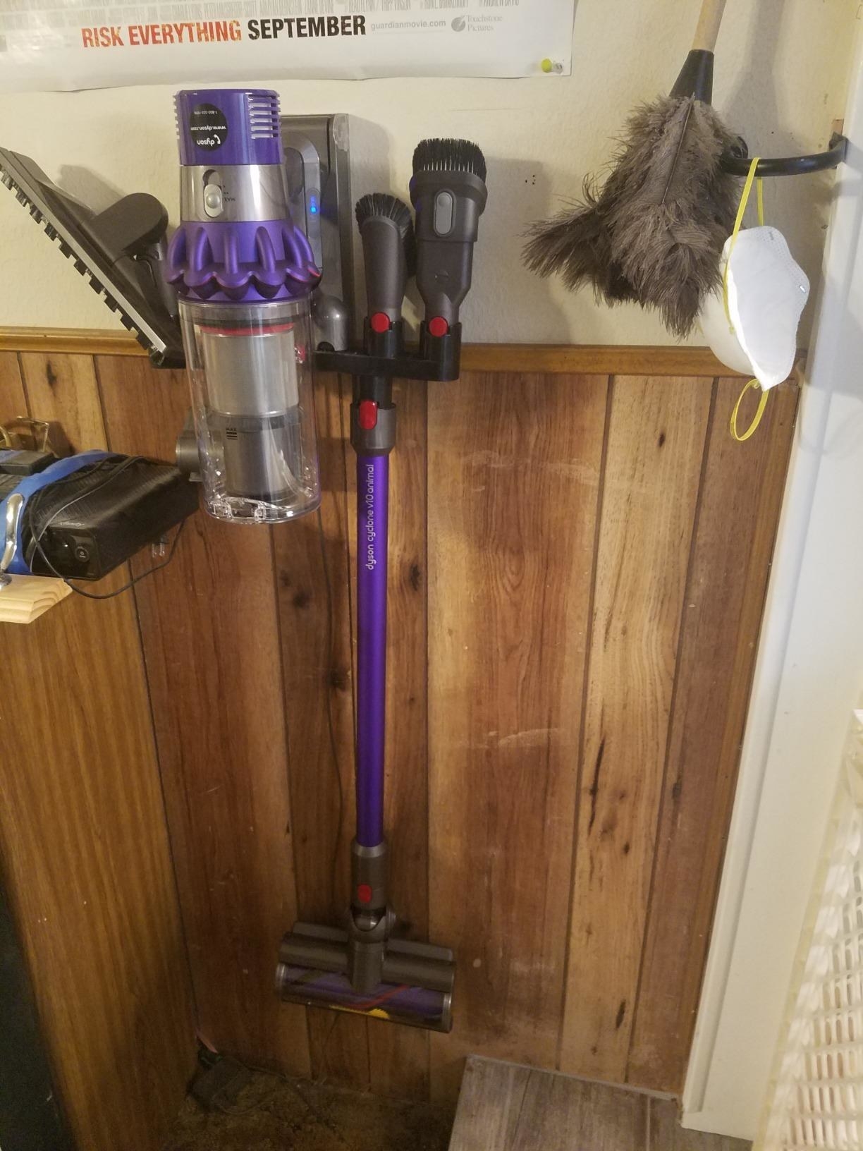 a reviewer photo of the purple vacuum hanging on its wall dock