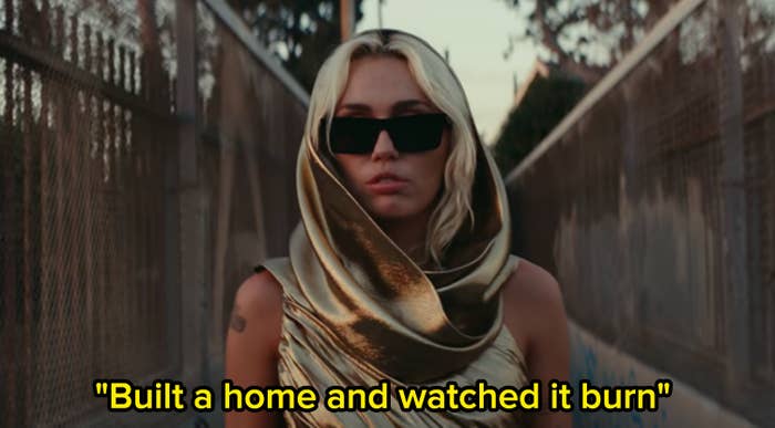 Miley Cyrus in the &quot;Flowers&quot; music video with the lyrics &quot;built a home and watched it burn.&quot;