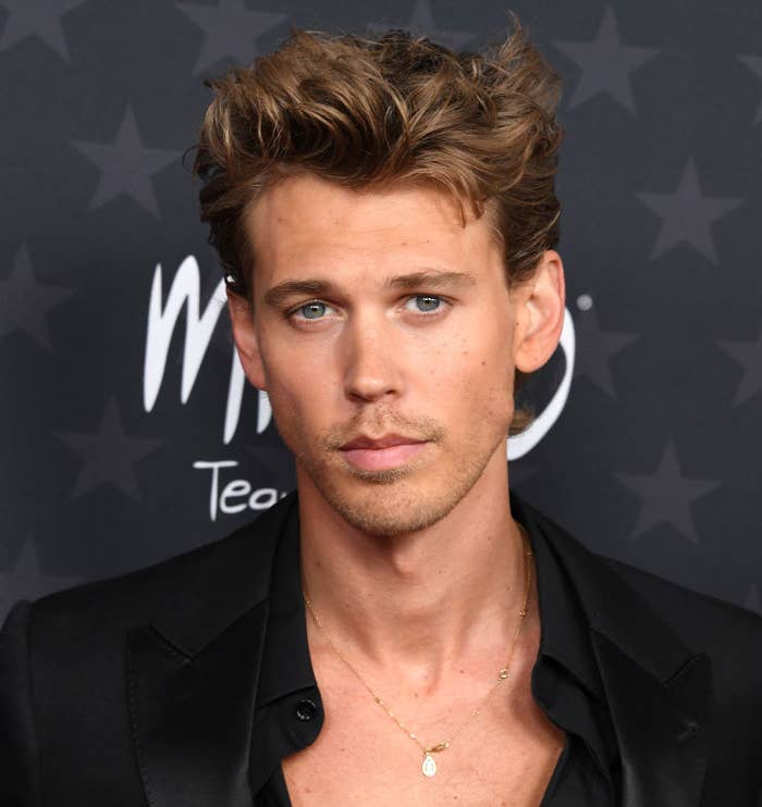 A closeup of Austin at a red carpet event wearing a button-up shirt and chain necklace
