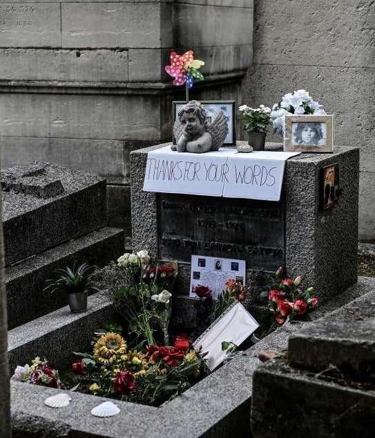 A simple square grave with lots of flowers, pictures, and gifts laid on top of it