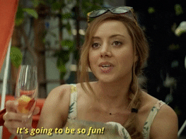 Woman holding a champagne glass and saying &quot;It&#x27;s going to be so fun!&quot;